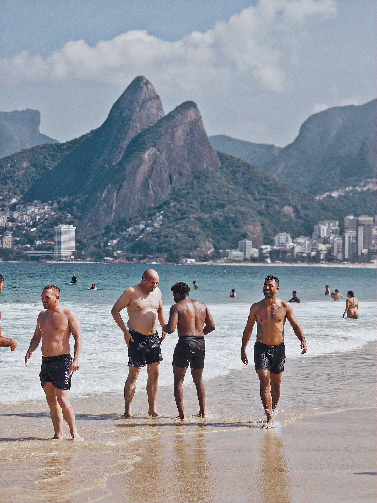 OSS Rio Tour members walking out of the surf with Dois Irmãos behind them